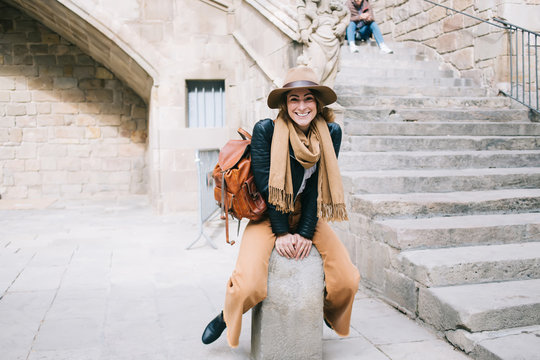 Happy woman sitting next to stairs of old building