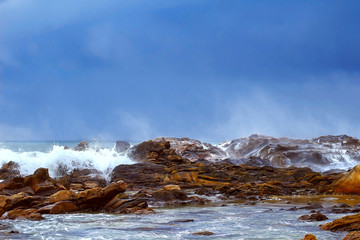 view of an ocean wave splashes on a rocky beach and deep sky