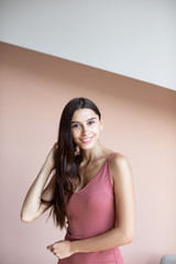 Obraz premium Beautiful woman with long hair is smiling indoors on wall background.