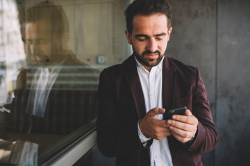 Bearded businessman using smartphone near window