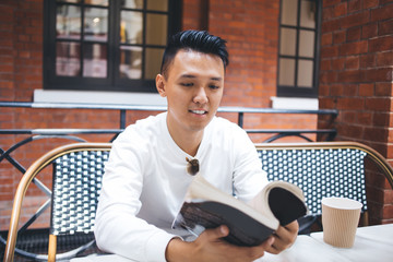 Young man spending time with book in cafe
