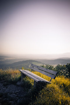 Lonely bench with great view standing in morning light on top of a mountain