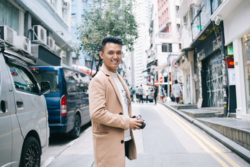 Fototapeta premium Joyful adult ethnic guy with camera in downtown