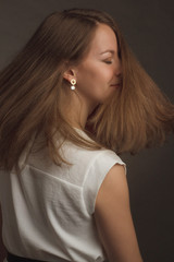 portrait of a brown-haired model in a white dress on a dark background in the Studio.