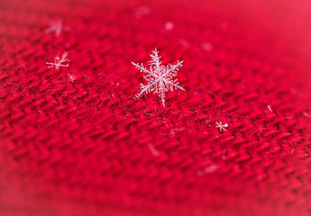 delicate macro image of a snowflake on red background.  soft defocused, shallow depth of field with plenty room for text/copy. 