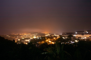 City lights of the historic city centre of Ouro Preto, Brazil, glowing in the rainstorm and reflecting in the clouds lighting up the night sky