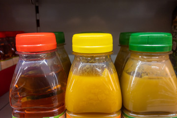 Fruit juice in bottles on the shelf with red, yellow and green screw caps