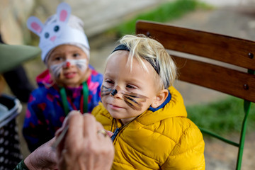Adorable blond toddler child with bear mask and painted face