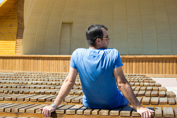 The man sitting alone in her back among many benches