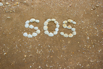Inscription on sand from shells - sos, camping, hiking danger