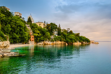 Fototapeta na wymiar Glavanovo beach in Rijeka, Croatia with steep cliffs and lush green trees