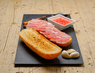 Toast of bread with acorn-fed Iberian ham on stone slate