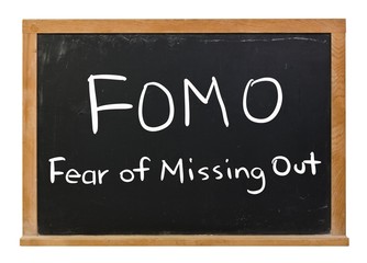 Obraz premium FOMO written in white chalk on a black chalkboard isolated on white