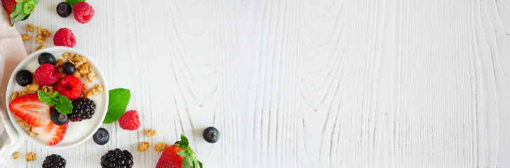 Healthy yogurt with fresh berries and granola. Banner with corner border against a white wood background. Copy space.