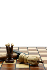 Fototapeta na wymiar Brutal Checkmate: A Queen And A Hammer Next To A Defeated White King On A Wooden Chess Board With White Background