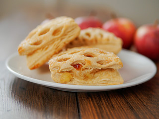 Apple lattice on a white plate on a wooden table, red apples in the background., Selective focus, Pastry product.,