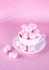 Pink marshmallows background in a white cup, dessert pastel tones, sweet dishes. Background or texture of colorful mini marshmallows