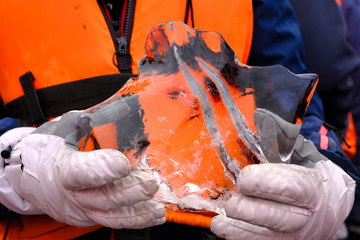 Fototapeta premium Young woman is taking a boat trip to Jokulsarlon Glacier Lagoon in Iceland. She is holding a large piece of ice