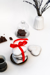 Valentine's Day still life with cup of coffee, chokolate and plate with heart shaped ginger cookie on white background. Valentines Day celebration concept