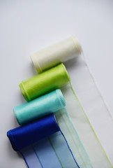 Reels organza ribbon pastel colors white blue green isolated white background. Vertical Design concept for Sewing and handcraft subject. Top view with Copy space