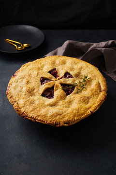 Fruit pie with plums and thyme on dark blue background