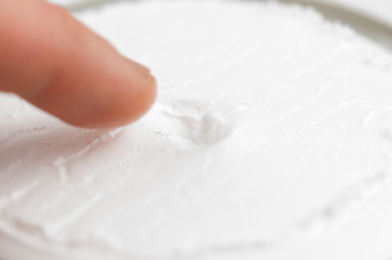 Closeup image of a man taking a hand cream with his finger. Copy space.