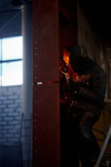 welder working with electrode at semi-automatic arc welding in manufacture production plant.Selective focus