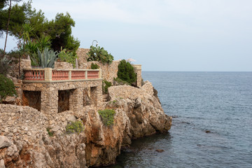 Terrace with green plants on stone seashore. Cap d'Antibes hiking trail. 