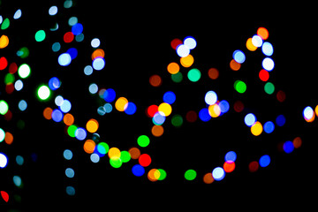 Lights from Christmas garlands defocused in beautiful bokeh. Bokeh colorful multi-colored lights yellow red blue green. Blurry lights Christmas mood. Copy space on background of multi-colored.