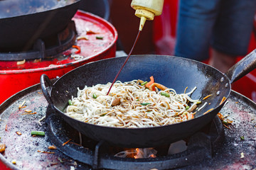 chef cooks Chinese noodle wok at street food festival