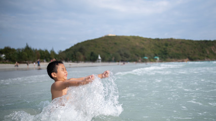 Boy playing  on sandy beach.  Happy kid on vacations at seaside on summer holidays. Children in nature with sea, sand and blue sky.
