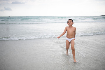 Boy playing  on sandy beach.  Happy kid on vacations at seaside on summer holidays. Children in nature with sea, sand and blue sky.