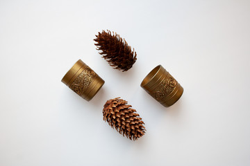 Glossy golden candle holders and pine cones isolated on white background from a high angle view