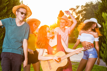Young friends singing and dancing in park. - obrazy, fototapety, plakaty