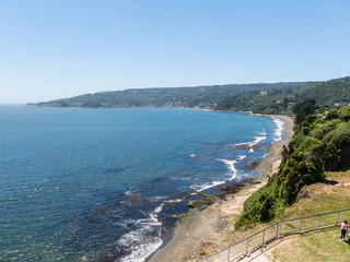 Fototapeta premium Beach lovers facing the Pacific Ocean from the fort of Niebla village. Estuary and mouth of the Valdivia River. Valdivia, Los Rios Region, South of Chile