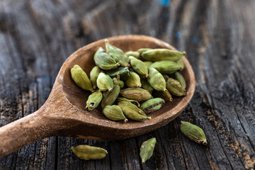 Cardamom in wooden spoon isolated on a wooden background
