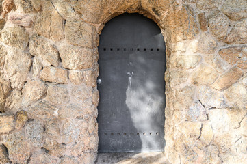  old metal door in  stone wall. Barcelona, Spain. Catalonia