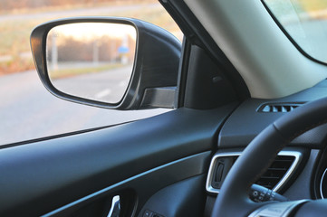 Obraz na płótnie Canvas Car interior with a side-view mirror and countryside road