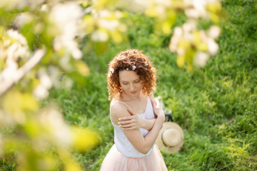 Obraz premium Young attractive girl walks in spring green park enjoying flowering nature. Healthy smiling girl spinning on the spring lawn. Allergy without