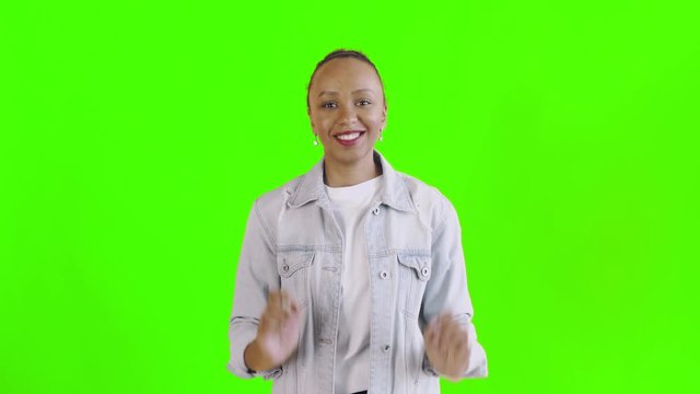 Beautiful happy african young woman surprised while looking at the camera and saying OH MY GOD on green background Jean jacket