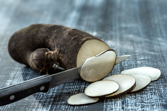 Three Long Black Winter Radishes Raphanus Sativus Subsp. Niger And A Cut One On A Wooden Background