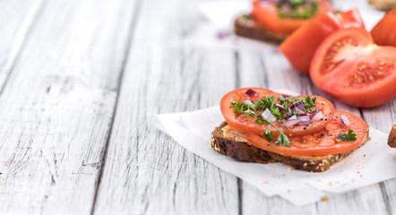Some Tomato Sandwich on a vintage wooden table (selective focus; close-up shot)