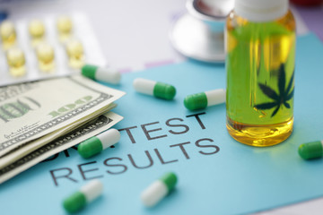 Pills jar of marijuana oil on blue envelope with inscription test result.