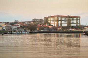 Santa Clara Convent in Vila do Conde, Portugal, at sunset on an autumn day, with the river Ave in the foreground.