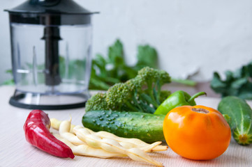 Harvest on the table, harvesting vegetables: red and green peppers, cucumbers, broccoli, asparagus beans, yellow tomato. Blender for cutting