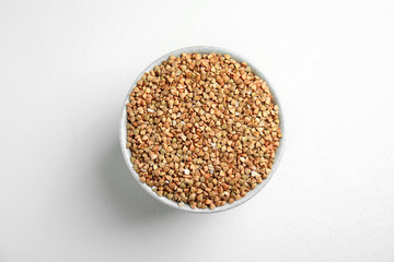 Bowl with green buckwheat on white table, top view