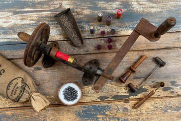 Antique tools for reloading of hunting cartridges, powder measure, cartridge wad tampers, a lot of small bags with lead shots on a wooden background
