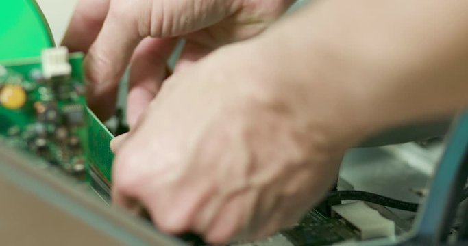 A computer technician replacing or adding random access memory or RAM to a desktop computer he is repairing.