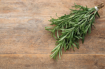 Bunch of fresh rosemary on wooden table, above view. Space for text