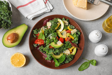 Tasty fresh kale salad on light grey table, flat lay